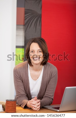 smiling saleswoman leaning on counter in a decorator shop