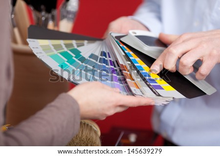 Interior decorator in a meeting with a client discussing various paint colors from a colorful set of swatches he is holding in his hand