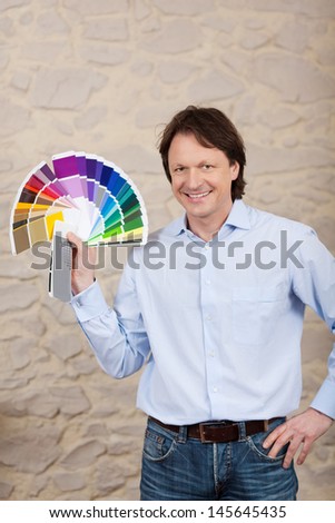 Smiling male decorator or painter with a colorful display of paint sample color swatches in his hand