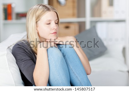 Young woman taking a nap while sitting on sofa at home