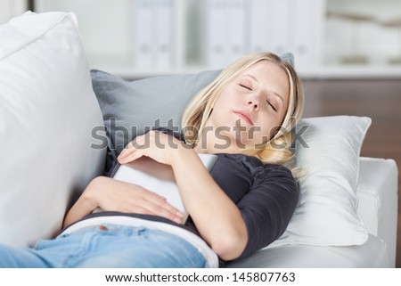 Young woman with digital tablet sleeping on sofa at home