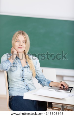 Portrait of confident young female student sitting at desk in classroom