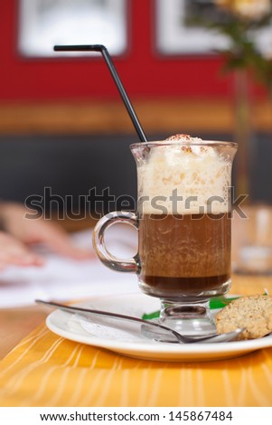 Glass of delicious iced coffee standing on a restaurant or coffee house counter topped with rich creamy vanilla ice cream