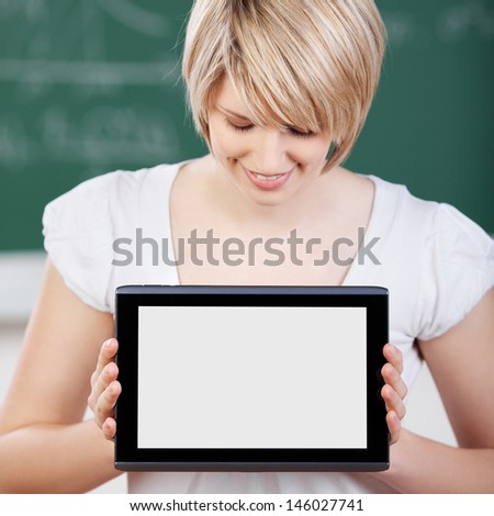 Pretty young blond student displaying the screen of her tablet-pc holding it up towards the camera with blank white copyspace for your text, advert or photo