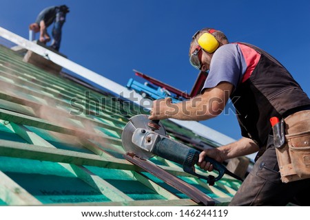 Roofer Using A Hand Circular Saw To Cut A Roof-Tile