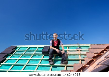 Roofer resting on top of a new unfinished roof