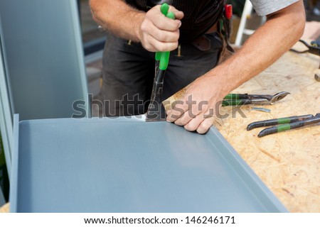 Roofer folding a metal sheet using special pliers with a large flat grip