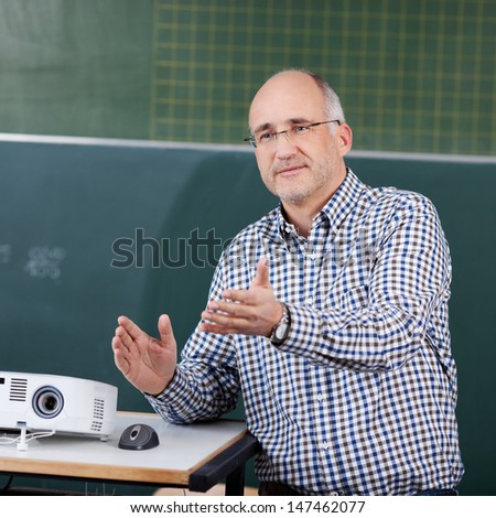 Male professor with projector and mouse gesturing in classroom