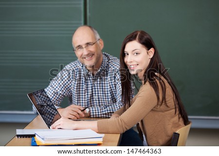 Pretty young female student and middle-aged male university or college lecturer working on a laptop together