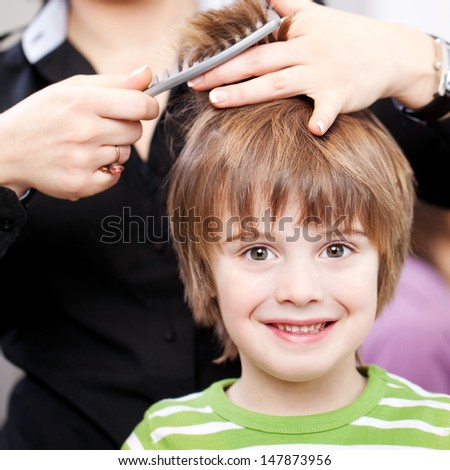 Beautiful young child with large expressive eyes at the hairdresser having a haircut