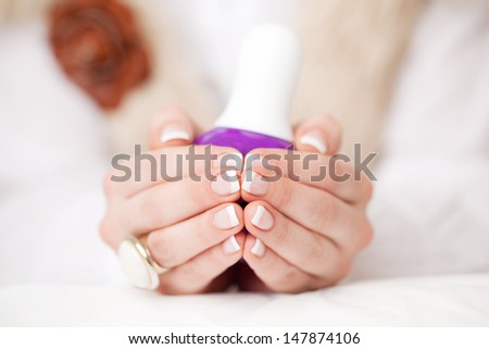 Woman displaying her manicured French nails holding the tips of her fingers together, close up view