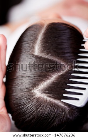 Overhead View Of The Top Of A Brunette Woman Showing A New Creative Hairstyle With A Zig Zag Path With A Portion Of The Hairdressers Comb In View