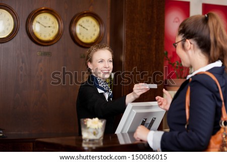 Guest at an international hotel requesting a business card at reception from the beautiful stylish receptionist