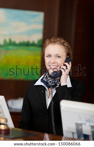 Young attractive female receptionist answering the phone in a hotel