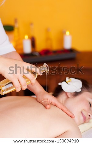 Happy woman laying face-down while receiving a massage with aromatic oil in a beauty center