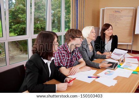 group sitting at table and listening to someone in a meeting