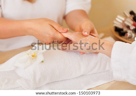 beautician applying lotion on women\'s hand