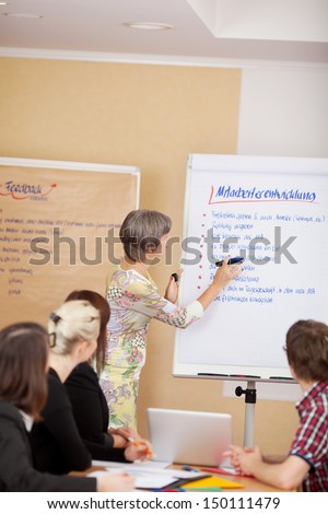 Woman giving a presentation on a flipchart to a group of young business students