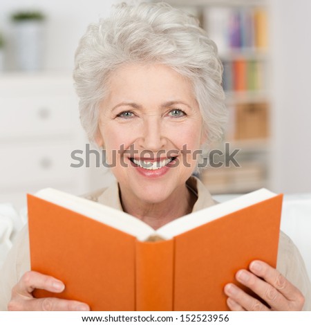 Attractive Grey Haired Senior Woman With A Lovely Smile Relaxing At Home Reading A Book