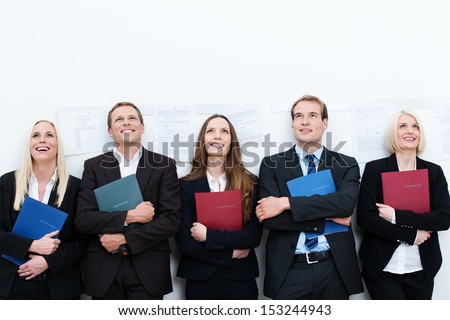 Group Of Happy Applicants For A Job Sitting In A Long Row With Smiles On Their Faces Clutching Their Curriculum Vitae