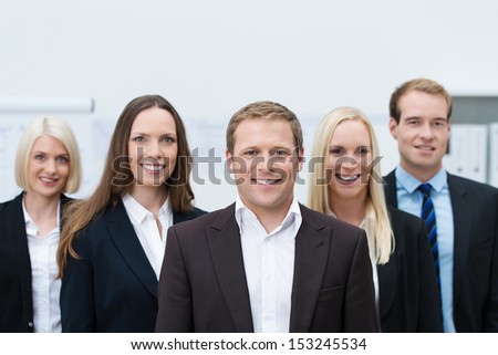 Happy professional young team made of three women and two men, all Caucasian, looking at camera and wearing formal suits and shirts