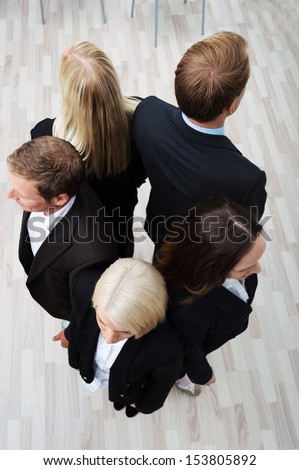 High angle view of a group of young businesspeople standing back to back facing outwards in a circle