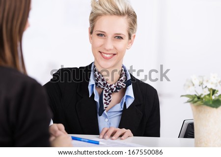 Friendly Beautiful Receptionist Standing Behind The Counter Assisting A Guest To Check Into A Hotel
