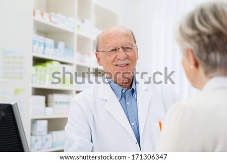 Elderly male pharmacist talking to a senior patient with a view over the womans shoulder to his face