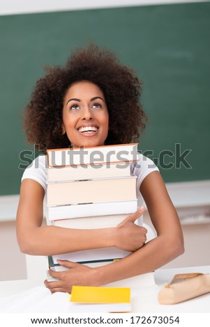 Joyful attractive young African American student hugging her text books as she realizes her dream to attend university