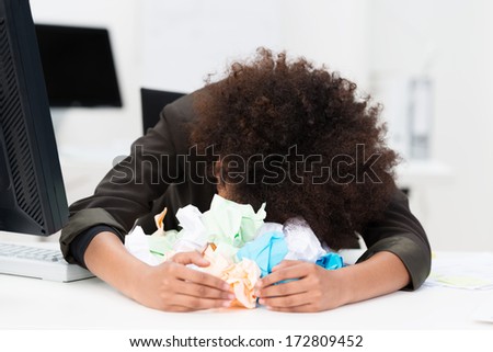 Distraught Writer Or Businesswoman With Her Head Lying On Her Desk In A Pile Of Crumpled Paper As She Suffers From Writers Block Or A Total Inability To Come Up With A Solution To A Problem