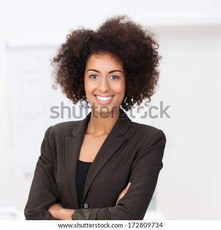 Beautiful Young Vivacious African American Businesswoman In A Stylish Jacket Standing With Her Arms Folded Beaming At The Camera