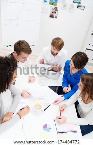 High angle view of a group of young business partners in a meeting seated around a table discussing a new project