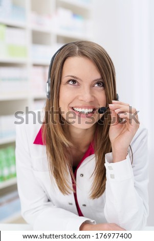 Friendly pharmacist taking a call from a patient smiling as she offers advice over the telephone headset