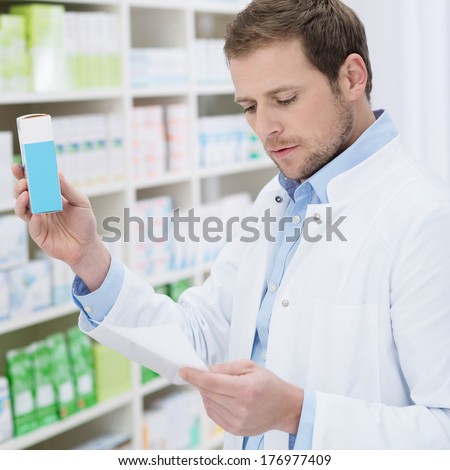 Pharmacist fulfilling a prescription holding medication in his hand as he checks the script