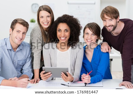 Successful Motivated Multiethnic Business Team Posing Grouped Around An Attractive African American Woman Looking At The Camera With Beaming Friendly Smiles
