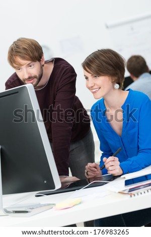 Attractive male and female co-workers working in cooperation at the office