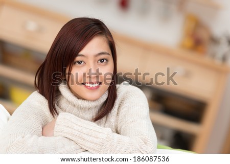 Portrait of an attractive young Asian woman relaxing with folded arms looking at the camera with a friendly smile