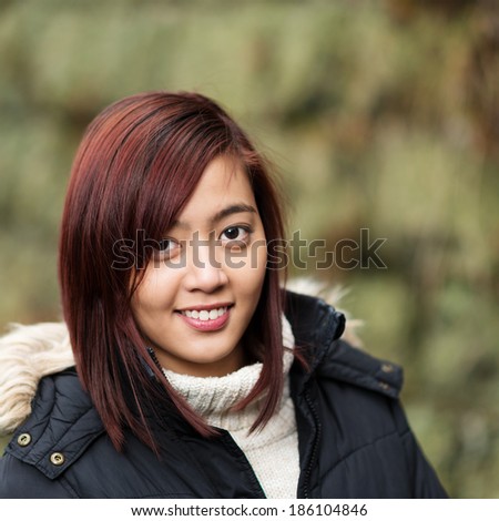 Pretty young Asian woman in winter fashion wearing a warm knitted polo neck sweater and warm jacket smiling at the camera