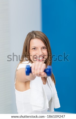Happy young woman full of vitality working out at the gym with dumbbells in a health and fitness concept