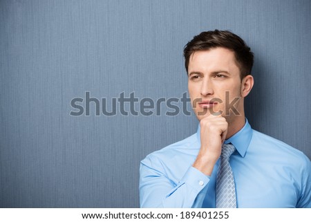 Thoughtful young businessman staring pensively into the distance as he tries to find inspiration or solve a problem, with copyspace