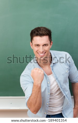 Motivated happy young man punching the air with his fist while giving the camera an enthusiastic smile