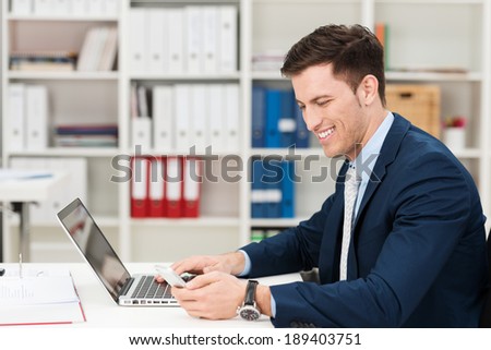 Businessman doing online banking sitting at his desk entering the details of his bank card into his laptop computer