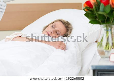 Sick woman resting peacefully in hospital lying asleep in a bed on a ward as she recuperates from an injury or illness