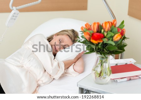 Attractive middle-aged female patient lying sleeping peacefully in a hospital bed as she recuperates from an injury, surgery or illness
