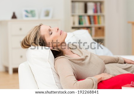 Woman having a nap on the sofa relaxing with her head tilted back on the cushion and eyes closed