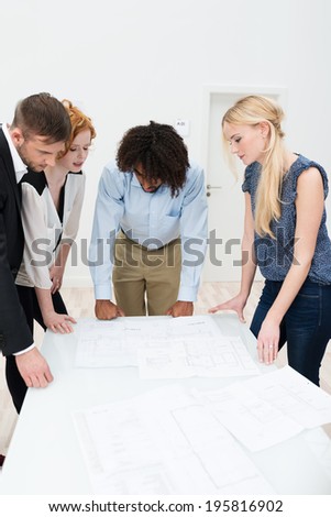 Multiethnic business team in a meeting standing around a table in the office discussing paperwork and brainstorming ideas