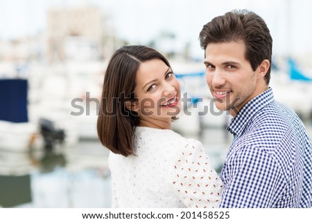 Attractive couple turning to look back at the camera with a friendly smile as they walk away