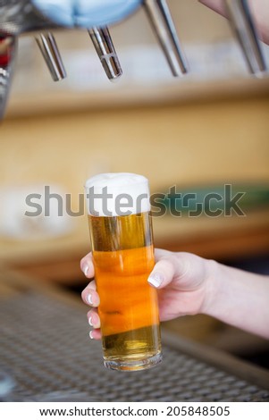 Cropped image of bartender\'s hand filling beer in glass at restaurant