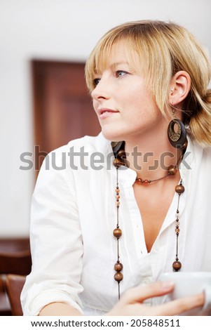 Upper body close up profile portrait of an attractive young blond woman with a calm expression watching something off frame