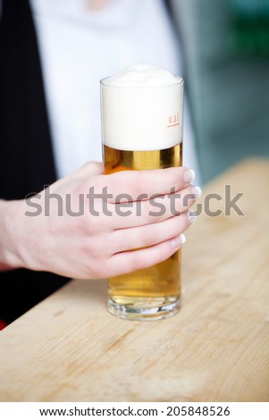Closeup of woman\'s hand holding beer glass in restaurant